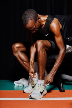 a man tying his shoes while sitting on a chair