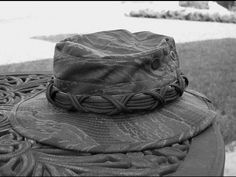 a black and white photo of a hat sitting on top of a metal table outside