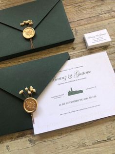 two green envelopes with gold buttons on them and some white paper next to each other