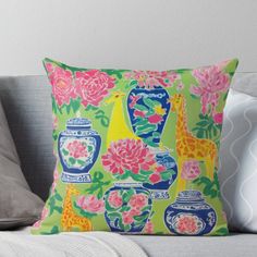 a colorful pillow with flowers and giraffes on it sitting on a couch