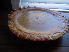 a pie sitting on top of a wooden table next to a white window sill