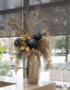 a vase filled with blue and gold flowers on top of a marble counter next to a window