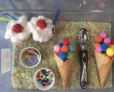 two ice cream cones with pom - poms and spoons on a table