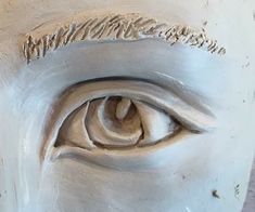 an eye is shown in the center of a statue's face, which appears to be made out of clay