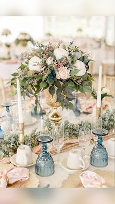 the table is set with candles, plates and flowers in vases on top of each other