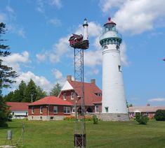 a light house sitting on top of a lush green field next to a red and white building