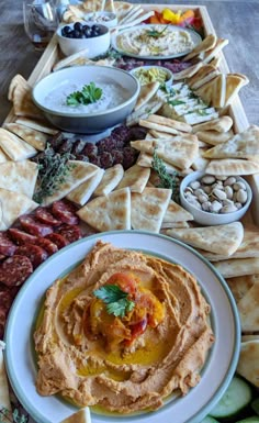 an assortment of snacks and dips are arranged on a platter with crackers