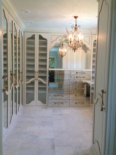 a large walk in closet with glass doors and chandelier