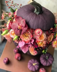 an arrangement of flowers and pumpkins on a table