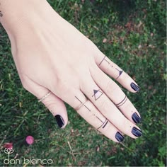 a woman's hand with black and white tattoos on it, holding onto her fingers