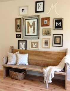 a wooden bench sitting in front of a wall filled with framed pictures and other items