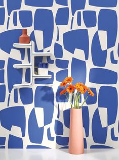 a vase with orange flowers in front of a blue and white geometric wallpaper design