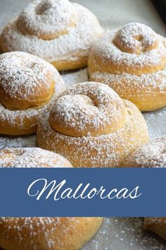 several powdered sugar donuts on a baking sheet with the words mallorcas above them