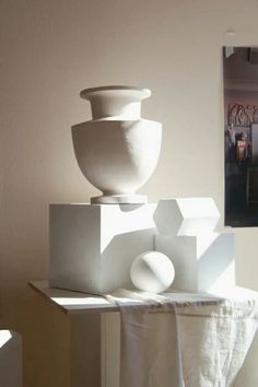 three white vases are stacked on top of each other in front of a mirror