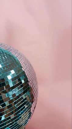 a mirror ball sitting on top of a wooden table next to a pink wall in the background