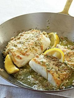 two fish fillets in a pan with lemon slices