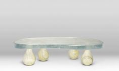 an oval glass table with three white shells on the bottom and two legs in the middle