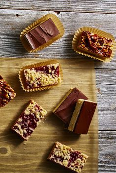 several pieces of dessert sitting on top of a wooden cutting board