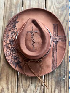 Hand burned Old Rugged Cross Hat. This hat includes a beautiful, rustic cross paired with a lovely floral design and the word faith in the center of the crown. Hatband is included. This beauty is perfect for your next concert, dinner date or any special occasion. It's simply stunning. Hats are one size fits most with a drawstring to adjust sizing. Fedora Hat Decorating Ideas, Wood Burned Hats Women, Burned Fedora Hat Designs, Hand Burned Hats, Burnt Cowboy Hat, Hat Band Ideas, Cowboy Hat Ideas, Felt Hat Burning Designs, Hat Burning Designs