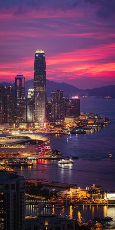 the city skyline is lit up at night with bright lights in the foreground and water below