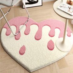 a heart shaped rug with pink and white designs on the floor next to a table