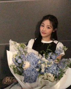 a woman holding a bouquet of blue and white flowers