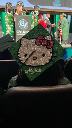 a hello kitty graduation cap sitting on top of a chair in front of a stage