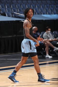 a basketball player is walking on the court with his hand in his pockets and wearing blue shoes