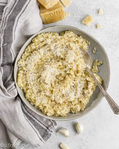 a bowl filled with rice and topped with parmesan cheese next to a spoon