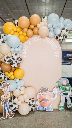 a large balloon wreath with toy story characters and balloons on the front, in an airport terminal