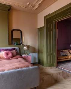 a bedroom with a bed, dresser and mirror in the corner next to an open door