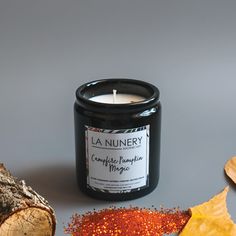 a candle sits next to some leaves and a piece of wood on a table with an autumn theme