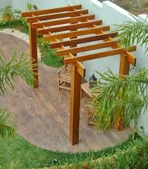 a wooden pergola sitting on top of a hard wood floor next to a white wall