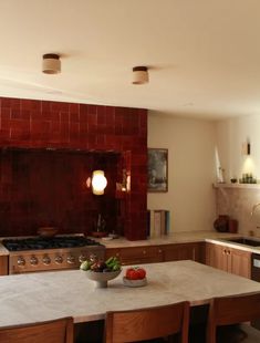 a kitchen with an oven, sink and table in the center is surrounded by wooden chairs