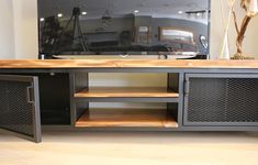 an entertainment center with metal mesh doors and wooden shelves in front of a flat screen tv