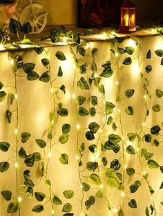 the curtain is covered with green leaves and fairy lights