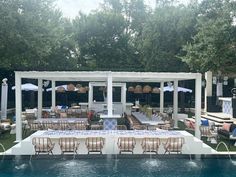 an outdoor dining area next to a pool with tables and chairs set up on it