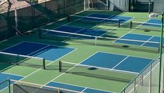 several tennis courts are lined up with blue and green court covers on top of them