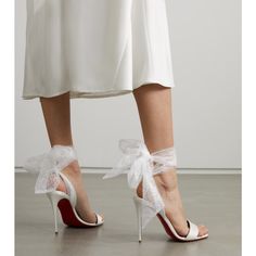 a woman's legs wearing white shoes with bows