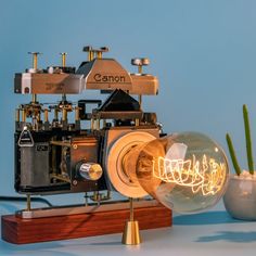 an old fashioned camera is sitting on top of a wooden stand with a light bulb in front of it