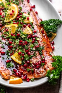 salmon with pomegranate, lemons and parsley on a white plate