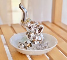 an elephant figurine sitting on top of a white bowl filled with silver jewelry