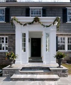 the front entrance to a house decorated with christmas wreaths and greenery on either side