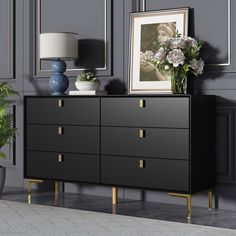 a black dresser with gold handles and drawers in a gray living room next to a potted plant