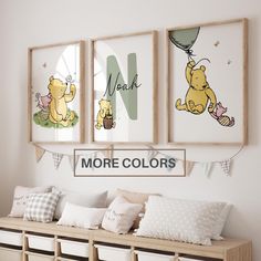 three winnie the pooh posters hanging above a bench with pillows and blankets on it