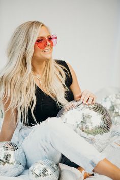 a woman sitting on top of a bed with disco balls