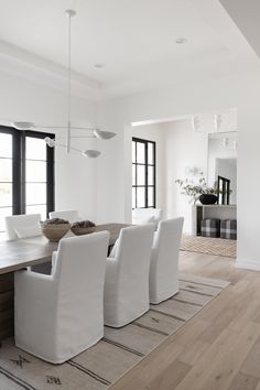 a dining room table with white chairs and a rug on the floor in front of it