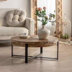 a coffee table with flowers in a vase on it and a birdcage next to it