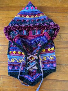 a multicolored knitted hoodie on a wooden floor