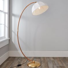 a floor lamp with a white shade on it and a gold plated metal base